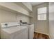 Laundry room with washer, dryer, window, shelf, and laminate wood floors at 8980 High Horizon Ave, Las Vegas, NV 89149