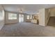 Open-concept living room with neutral carpet, lots of windows, and view to kitchen and backyard at 8980 High Horizon Ave, Las Vegas, NV 89149