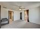 A carpeted bedroom featuring a ceiling fan and a glimpse into the ensuite bathroom at 971 Sable Chase Pl, Henderson, NV 89011