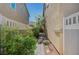 Cozy side yard featuring a stone-paved walkway, mature landscaping, and a white privacy fence and gate at 971 Sable Chase Pl, Henderson, NV 89011