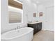 Elegant bathroom featuring a soaking tub, dark cabinets, and a window at 9993 Skye Gazer Ave, Las Vegas, NV 89166
