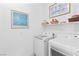 Bright laundry room with modern front-loading washer and dryer, and shelving at 9993 Skye Gazer Ave, Las Vegas, NV 89166
