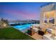 Twilight view of the gorgeous pool with a built-in hot tub and waterfall feature, surrounded by comfortable outdoor seating at 10 Sand Star Ln, Henderson, NV 89011