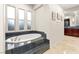 Bathroom featuring soaking tub with dark tile surround and window, with vanity and mirror visible in the background at 10412 Mansion Hills Ave, Las Vegas, NV 89144