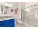 Bathroom featuring modern blue vanity, shower and bathtub combo with sliding glass door at 10412 Mansion Hills Ave, Las Vegas, NV 89144