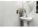 Close-up of a pedestal sink and mirror in a half bathroom, showcasing simple and clean design elements at 10604 Sariah Skye Ave, Las Vegas, NV 89166