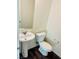 Powder bathroom features a pedestal sink, dark wood flooring, and a white toilet at 1163 Meadow Sparrow Pl, Henderson, NV 89011