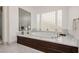 Spa-like bathroom featuring a soaking tub with marble surround and decorative privacy glass block windows at 1704 Wincanton Dr, Las Vegas, NV 89134