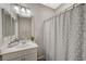 Well-lit bathroom features a shower with a geometric patterned shower curtain, and a single sink at 3164 Bormida Ave, Henderson, NV 89044