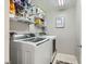Functional laundry room with modern washer and dryer, plus ample shelving for storage and supplies at 3177 Bivona Walk, Henderson, NV 89044