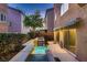Backyard with a small patio, green bushes, and elevated pool with tiered waterfall feature at 6075 Belvedere Canyon Ave, Las Vegas, NV 89139
