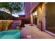 Backyard patio with a partial awning, a small elevated tiered pool and waterfall feature, and tall bushes at 6075 Belvedere Canyon Ave, Las Vegas, NV 89139