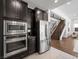 Kitchen featuring stainless steel appliances, dark cabinets, and easy access to the staircase at 7222 Pulsar Mesa Ct, Las Vegas, NV 89148
