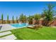 Backyard pool and patio area featuring chaise lounges and lush landscaping on a sunny day at 7222 Pulsar Mesa Ct, Las Vegas, NV 89148