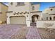 Tan home with a paver driveway, desert landscaping, and an arched entryway to the front door at 8043 Tank Loop St, Las Vegas, NV 89166