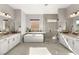 Spacious bathroom with dual vanities, soaking tub, and glass-enclosed shower, illuminated by natural light at 8575 Nicholas James Ave, Las Vegas, NV 89143