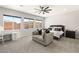Bright main bedroom with carpet, featuring a comfortable couch, windows, and a bed with decorative pillows at 8575 Nicholas James Ave, Las Vegas, NV 89143