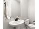 Clean powder room featuring a pedestal sink, sleek faucet, and a mirror, complemented by a toilet and towel rack at 8575 Nicholas James Ave, Las Vegas, NV 89143