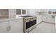 Bright kitchen featuring white cabinets, stainless steel appliances, marble backsplash, and quartz countertops at 8591 Cloudy Dawn Way, Las Vegas, NV 89113