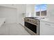 A modern white kitchen features stainless steel appliances, marble countertops, and sleek tile flooring at 8591 Cloudy Dawn Way, Las Vegas, NV 89113