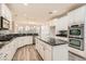 Modern white kitchen with stainless steel appliances, marble countertops and wood floors at 10235 Tresor Ct, Las Vegas, NV 89135