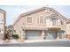 Two-story townhome featuring a three-car garage and a neutral color scheme with decorative stone accents on the facade at 10643 Petricola St # 103, Las Vegas, NV 89183
