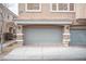 View of the two-car garage featuring stone pillars and modern gray doors, enhancing the townhome's curb appeal at 10643 Petricola St # 103, Las Vegas, NV 89183