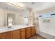 Bathroom with a double vanity, large mirror, tub, and tile surround at 10730 Amber Ridge Dr # 205, Las Vegas, NV 89144