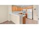 Open kitchen view showcasing wood cabinetry, modern white appliances, and a tiled floor at 10730 Amber Ridge Dr # 205, Las Vegas, NV 89144