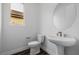 Modern half-bath with wood-look flooring, pedestal sink, and oval mirror at 11185 Black Fire Opal Dr, Las Vegas, NV 89138