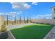 Landscaped backyard featuring artificial turf, a paved patio, and perimeter trees at 180 Native Stone St, Las Vegas, NV 89138