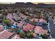 Aerial view of residential area featuring red roofs, swimming pools, and solar panels against a mountain backdrop at 2232 Barchetta Dr, Las Vegas, NV 89134