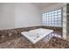 A modern white bathtub surrounded by marble countertops and a glass block window at 2232 Barchetta Dr, Las Vegas, NV 89134