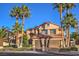 Two-story home featuring a three car garage, mature palm trees and well manicured landscaping at 2232 Barchetta Dr, Las Vegas, NV 89134