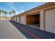 View of a garage with white doors opened and desert landscaping with palm trees in the background at 3740 Desert Marina Dr # 7, Laughlin, NV 89029