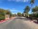 Elegant gated community entrance with brick-paved road, lush landscaping, and decorative gate under a bright blue sky at 4443 Verdiccio Ave, Las Vegas, NV 89141