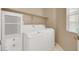 Laundry room with a white washer and dryer, upper shelf, and storage cabinet at 4443 Verdiccio Ave, Las Vegas, NV 89141
