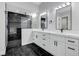 Modern bathroom features double sinks, sleek black and white tile and walk-in shower with glass enclosure at 5601 Mary Lou St, Pahrump, NV 89061