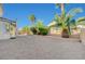 Back yard featuring desert landscaping with mature palms, gravel, brick border, and a covered patio at 5824 Farmhouse Ct, Las Vegas, NV 89141