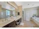 Bright bathroom with dual sinks, soaking tub and a glass enclosed shower with tile flooring at 5824 Farmhouse Ct, Las Vegas, NV 89141