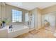Bright bathroom featuring a soaking tub, glass-enclosed shower, and modern fixtures and tile flooring at 5824 Farmhouse Ct, Las Vegas, NV 89141