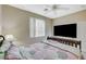 Cozy bedroom with a ceiling fan, window and television and bed with floral patterned comforter at 5824 Farmhouse Ct, Las Vegas, NV 89141