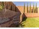 Landscaped backyard with stone steps and retaining wall with manicured trees at 6197 Jewel Vista St, Las Vegas, NV 89135
