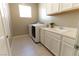 Well-lit laundry room featuring modern washer and dryer, sink with white cabinets and a window at 6197 Jewel Vista St, Las Vegas, NV 89135