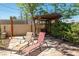 Backyard featuring stone patio, wooden pergola, mature landscaping, and two cushioned lounge chairs at 800 Kenny Way, Las Vegas, NV 89107