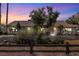 Wide front exterior view of this single-story home featuring desert landscaping, a brick driveway and mature trees at dusk at 800 Kenny Way, Las Vegas, NV 89107