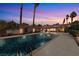 Backyard view of the swimming pool at dusk surrounded by desert landscaping and mature palm trees at 800 Kenny Way, Las Vegas, NV 89107