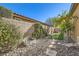 Landscaped backyard features decorative rock, artificial grass, privacy walls, and a young tree with vibrant orange fruit at 8514 Garnet Lake Ave, Las Vegas, NV 89113