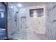 Modern walk-in shower featuring white marble tile surround, pebble flooring and glass enclosure at 913 Evening Fawn Dr, North Las Vegas, NV 89031