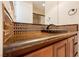 Vanity with bronze colored counter, dark cabinets, and decorated brown backsplash tiling with design at 9220 Tesoras Dr # 401, Las Vegas, NV 89144